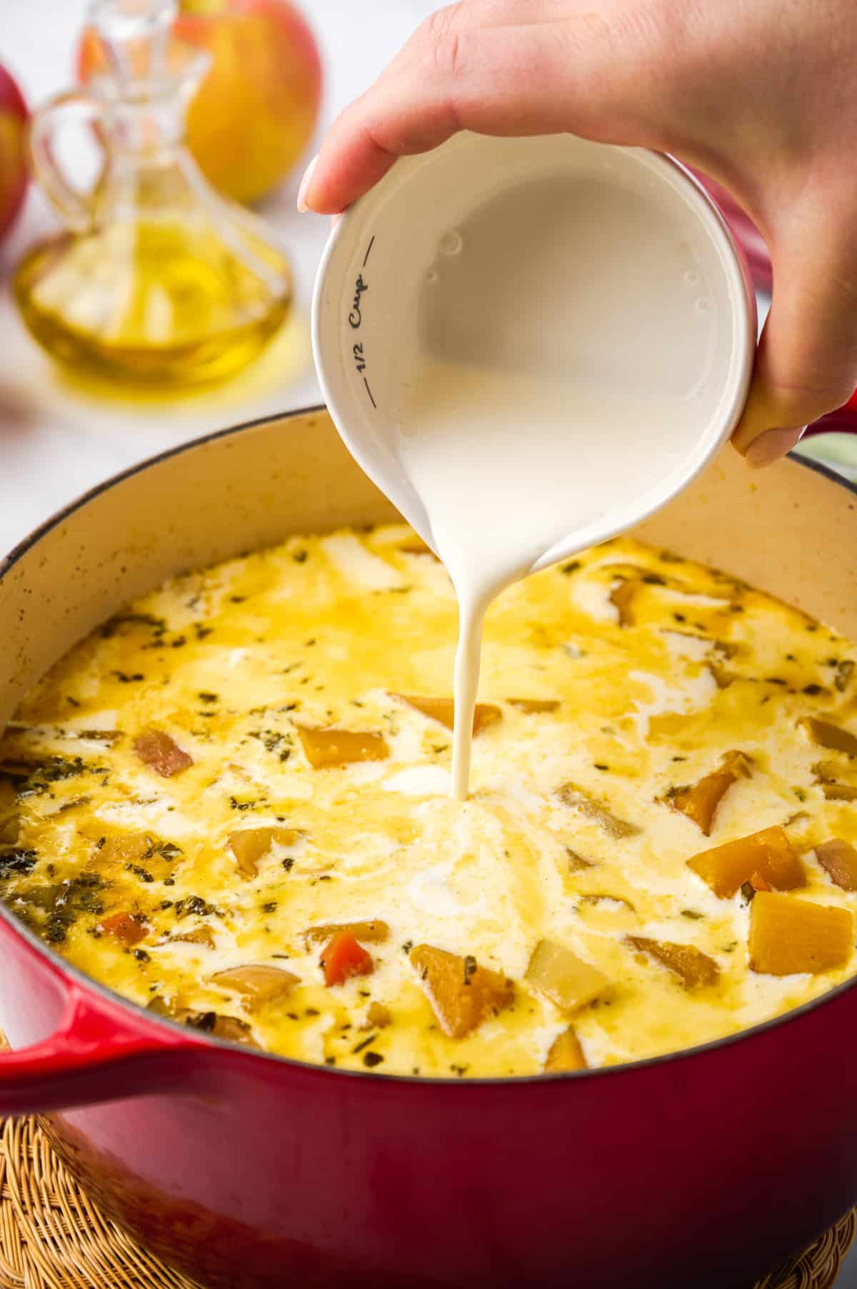 adding cream to butternut squash apple soup