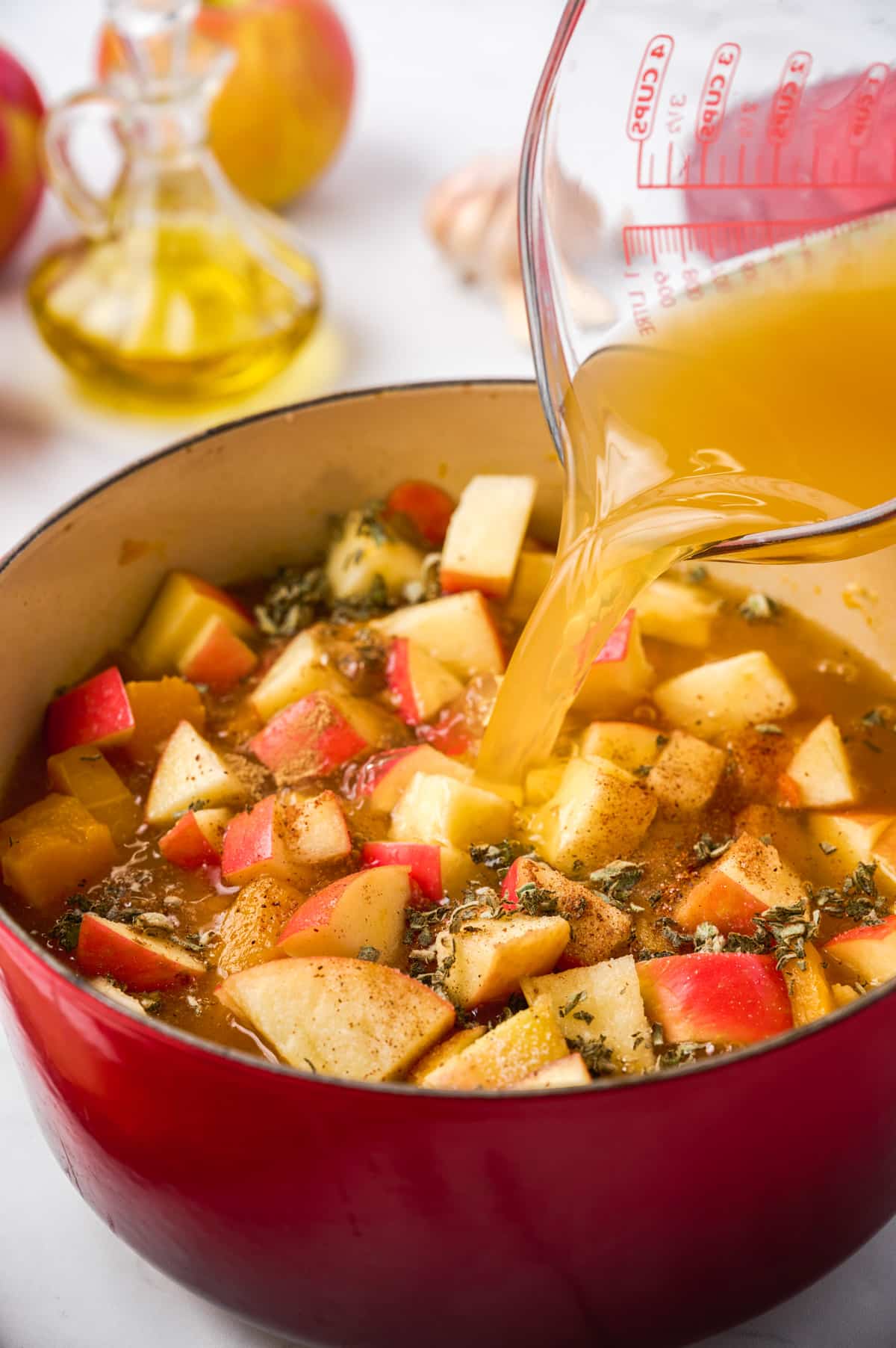 pouring broth into apple butternut squash soup