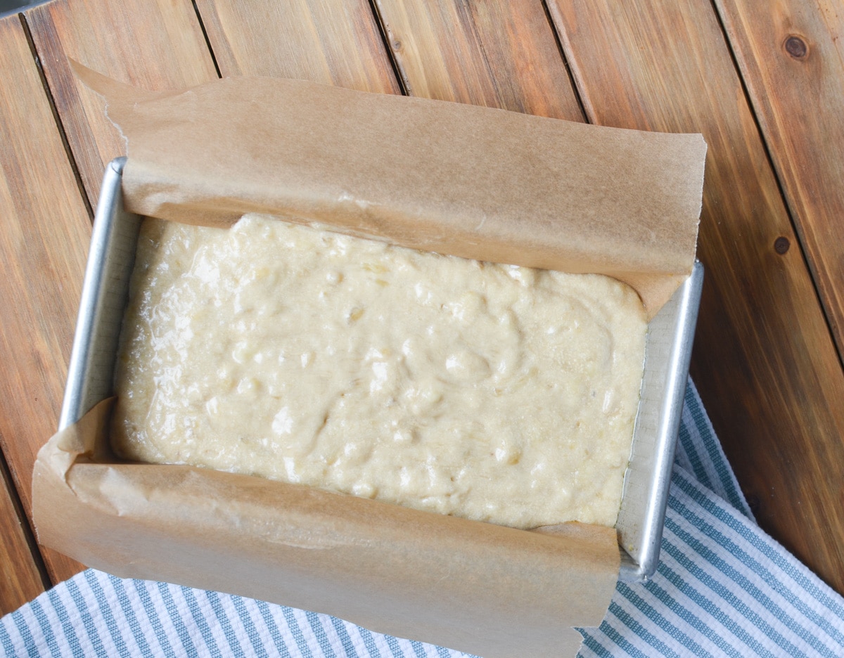 banana bread batter in parchment lined loaf pan.