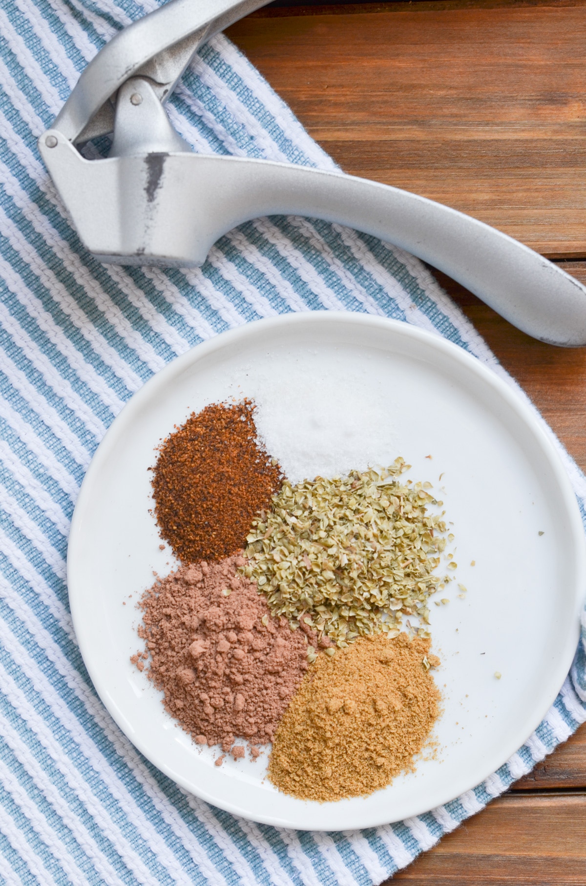 spices for black bean chili recipe on plate with garlic press.