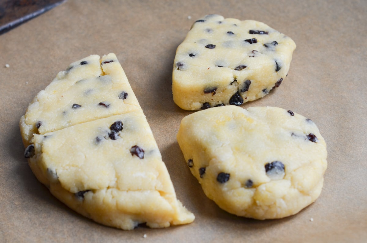 gluten-free scone dough cut int four pieces on parchment lined baking sheet.