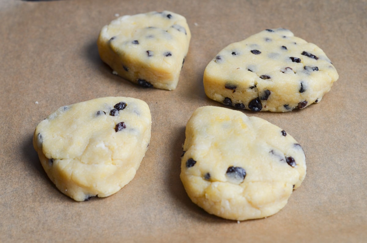 Four gluten-free scones on parchment lined baking sheet ready for the oven.