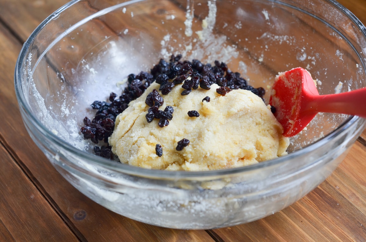mixing bowl with gluten-free scone dough and currants and spatula.
