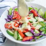 pouring salad dressing on salad.