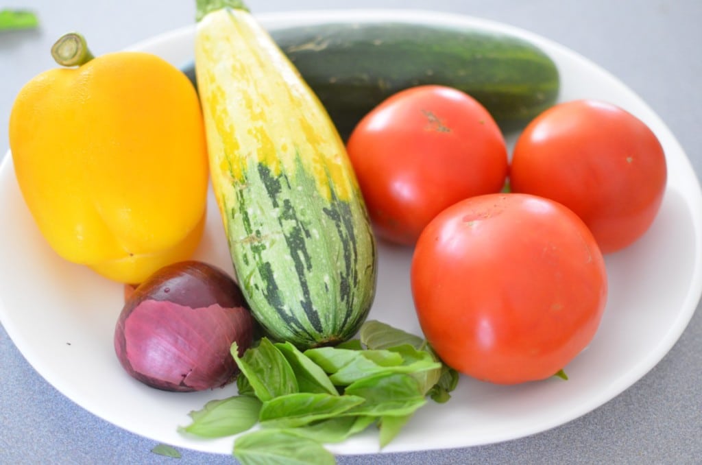 Farm Fresh Ingredients on a plate (yellow pepper, tomatoes, cucumber, squash and basil leaves)