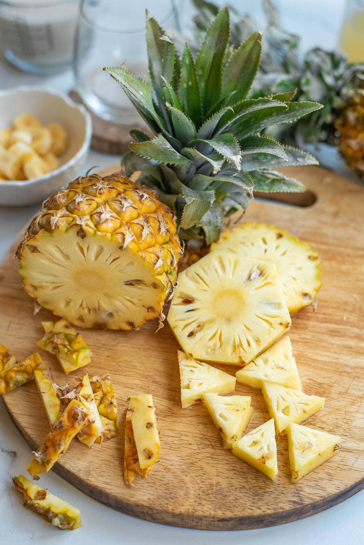 a cut pineapple with pieces on a cutting board.