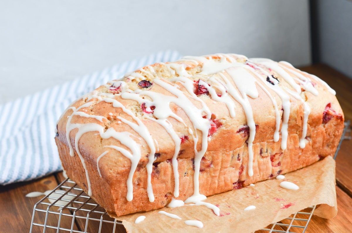 cranberry orange bread with icing in parchment paper.