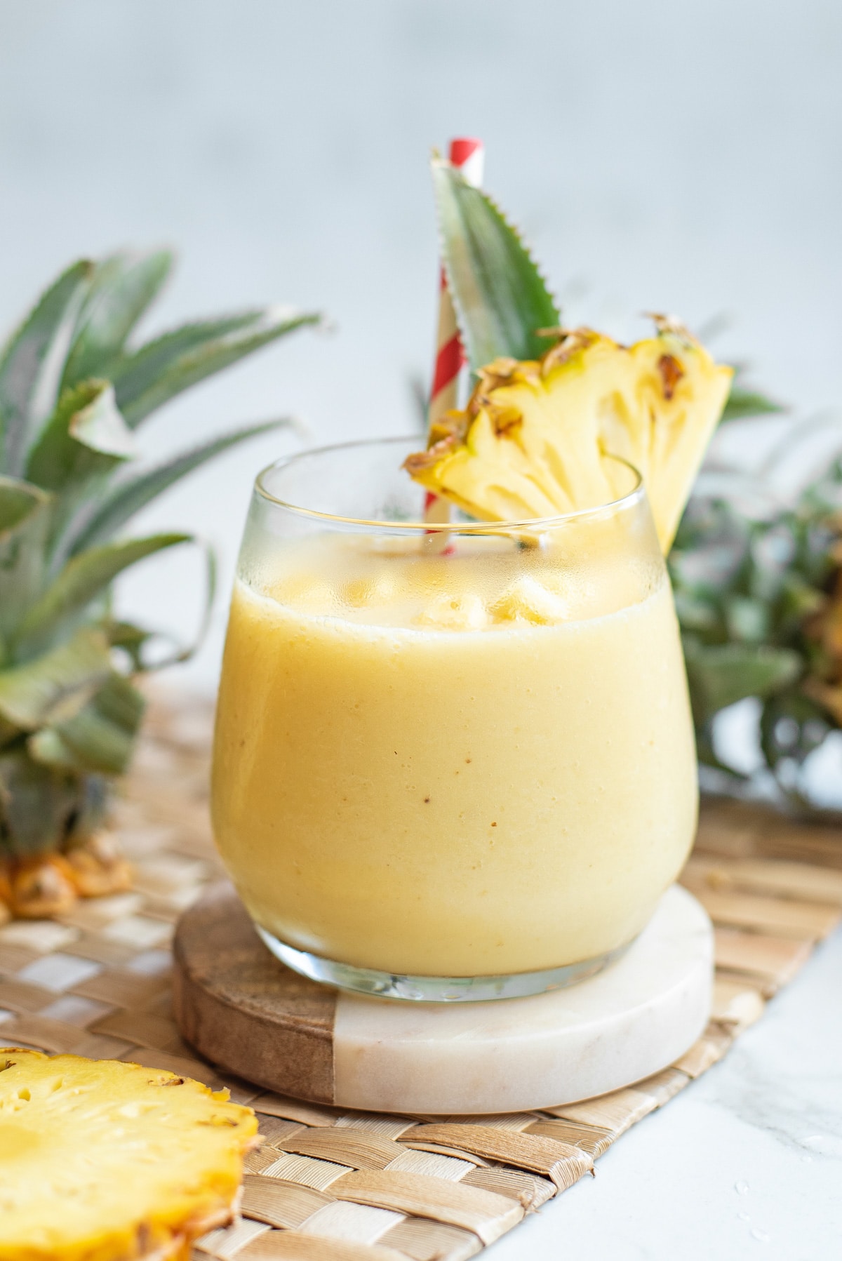 pineapple smoothie in a glass with a pineapple wedge as garnish.
