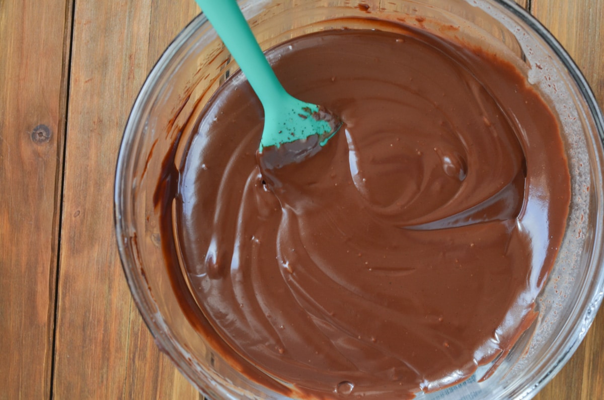 melted chocolate and coconut cream in mixing bowl with spatula.