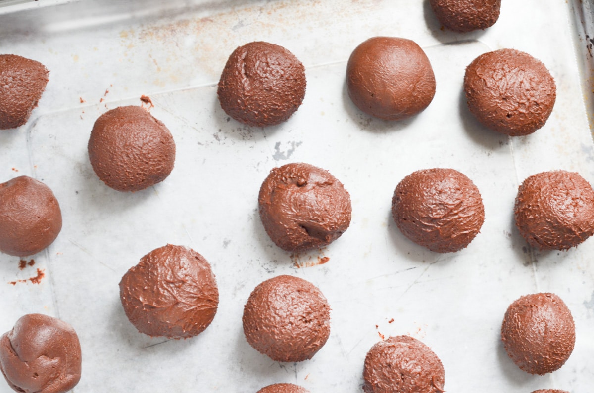 chocolate truffles balls on a parchment lined baking sheet.