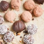 chocolate truffles with various toppings on a parchment lined baking sheet.