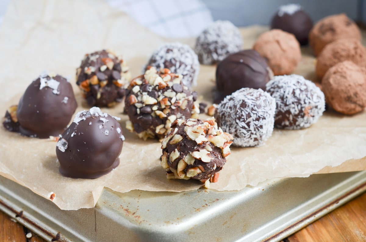 chocolate truffles with various toppings on parchment lined baking sheet.