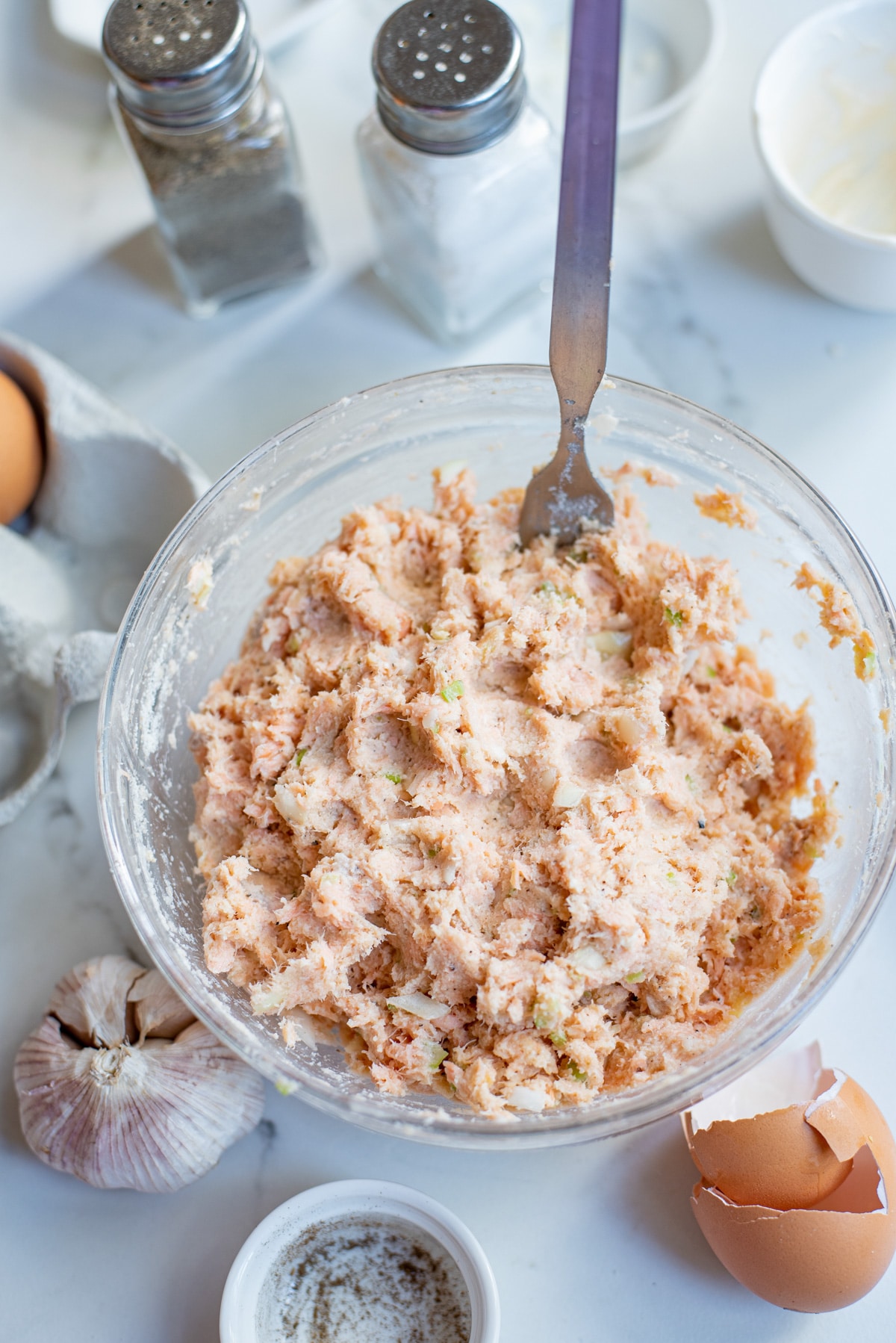 all ingredients for salmon cakes in a bowl with a spoon.