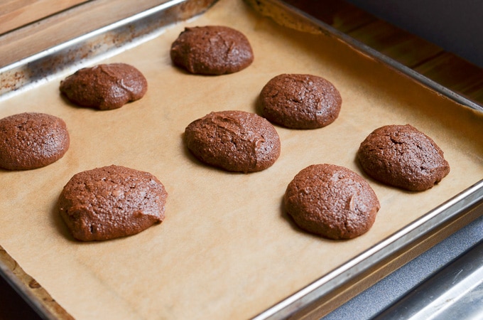 Chocolate fudge cookies baked on parchment lined baking pan.