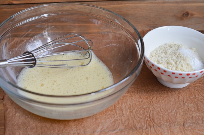 eggs in mixing bowl with whisk, bowl of dry ingredients on counter.