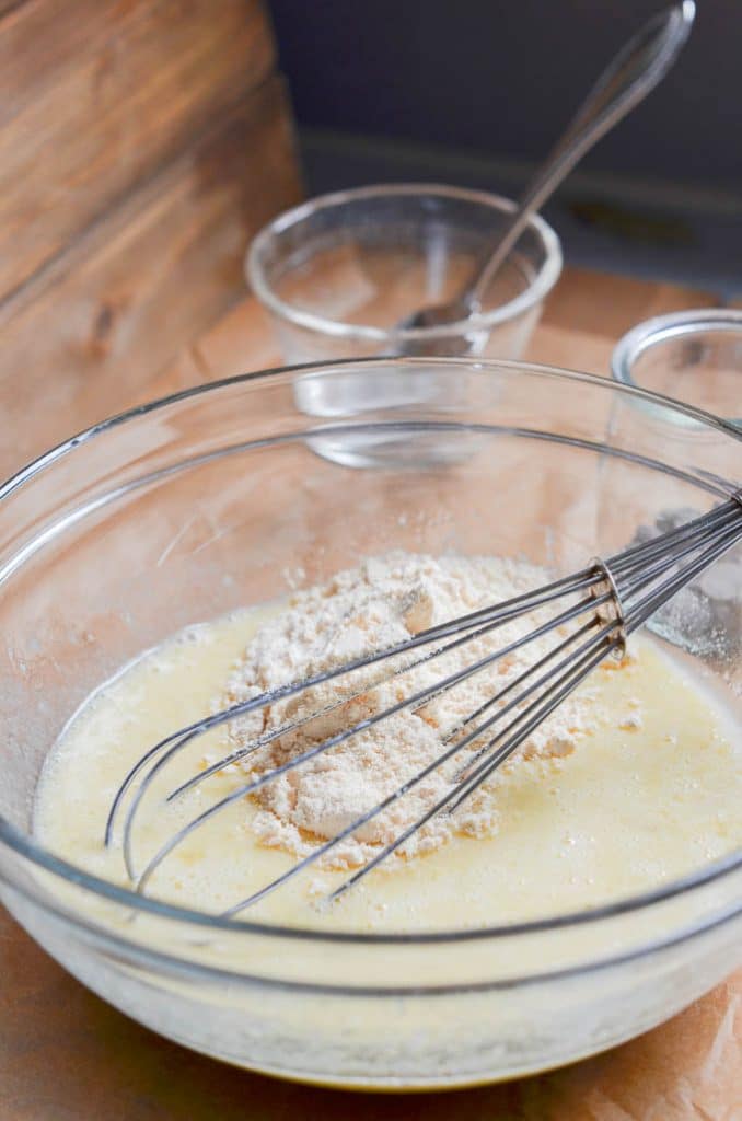 Adding dry ingredients to wet ingredients in mixing bowl, ready to whisk.