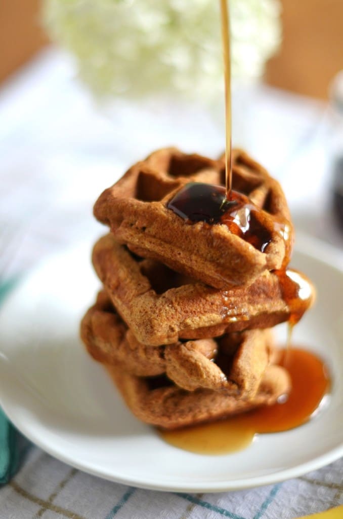 Paleo Pumpkin Waffles stacked on a plate with maple syrup- 24 Carrot Kitchen