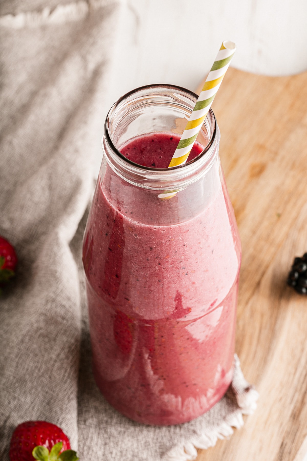 mixed berry smoothie in a glass bottle with straw.