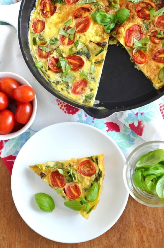 Paleo Fritatta in pan, slice on plate, bowl of tomatoes on table. - 24 Carrot Kitchen