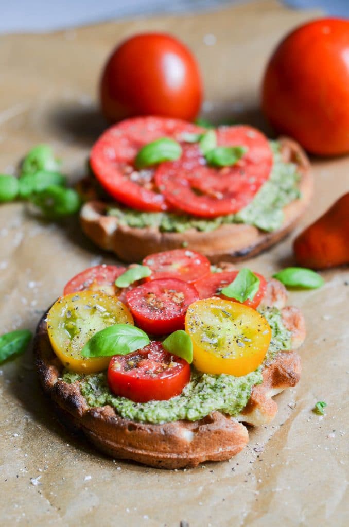 Paleo pesto on waffle with cherry tomatoes and basil leaves.