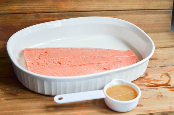 salmon in casserole dish and 1/2 orange glaze in measuring cup on counter.