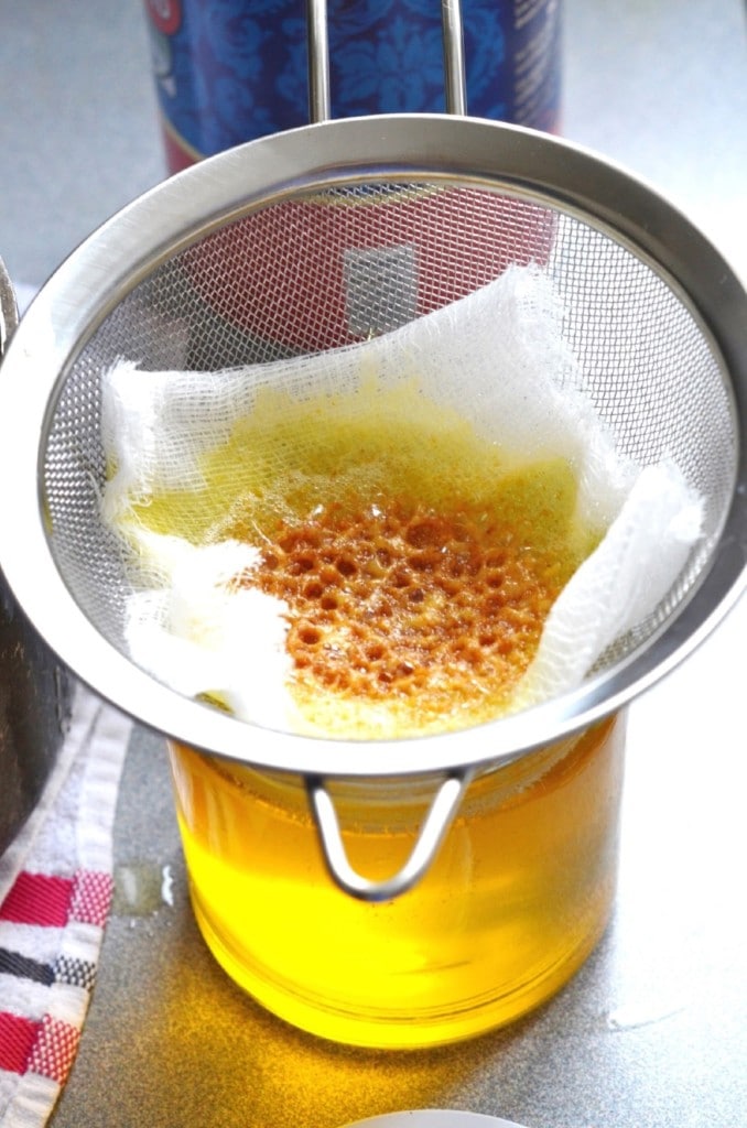 Melted butter in ghee strainer over glass jar - 24 Carrot Kitchen