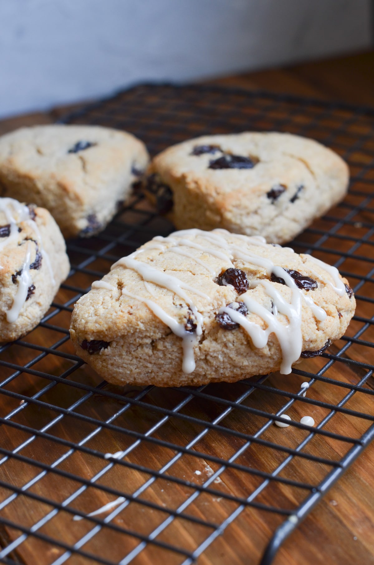 gluten-free cinnamon raisin scones with glaze on cooling rack.