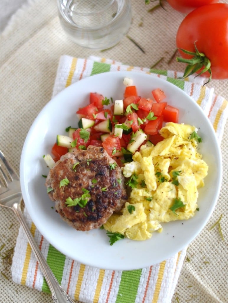 Whole30 sausage on plate with scrambled eggs and chopped tomatoes and zucchini - 24 Carrot Kitchen