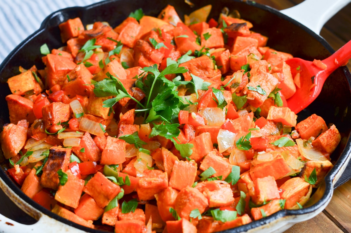 sweet potato hash in cast iron skillet with chopped parsley.