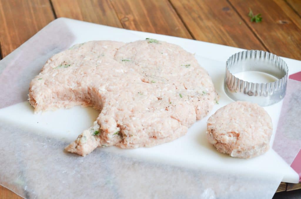 ground chicken on chopping block with circle cutter.