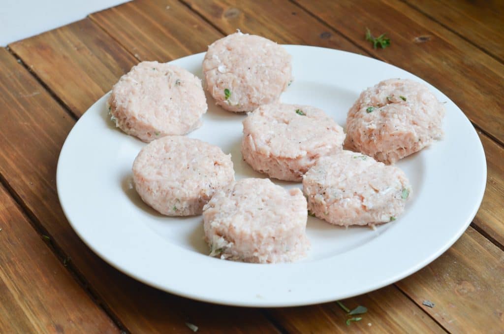 round raw sausage patties on plate.