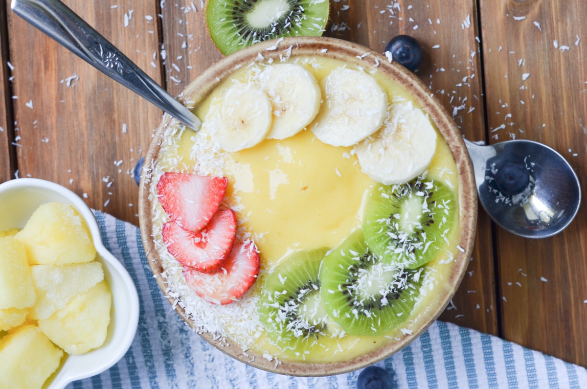 Mango Smoothie Bowl with toppings, sliced bananas, sliced kiwis, sliced strawberries.