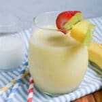 pina colada smoothie in a glass with garnishes.