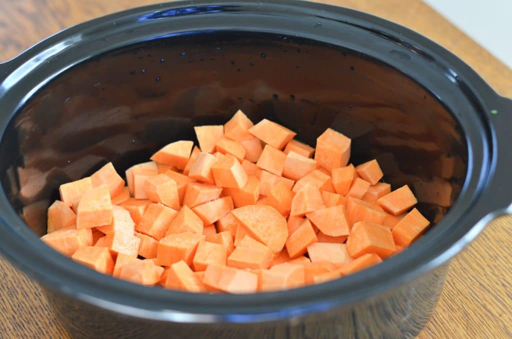 peeled and chopped sweet potato pieces in bottom of slow cooker.