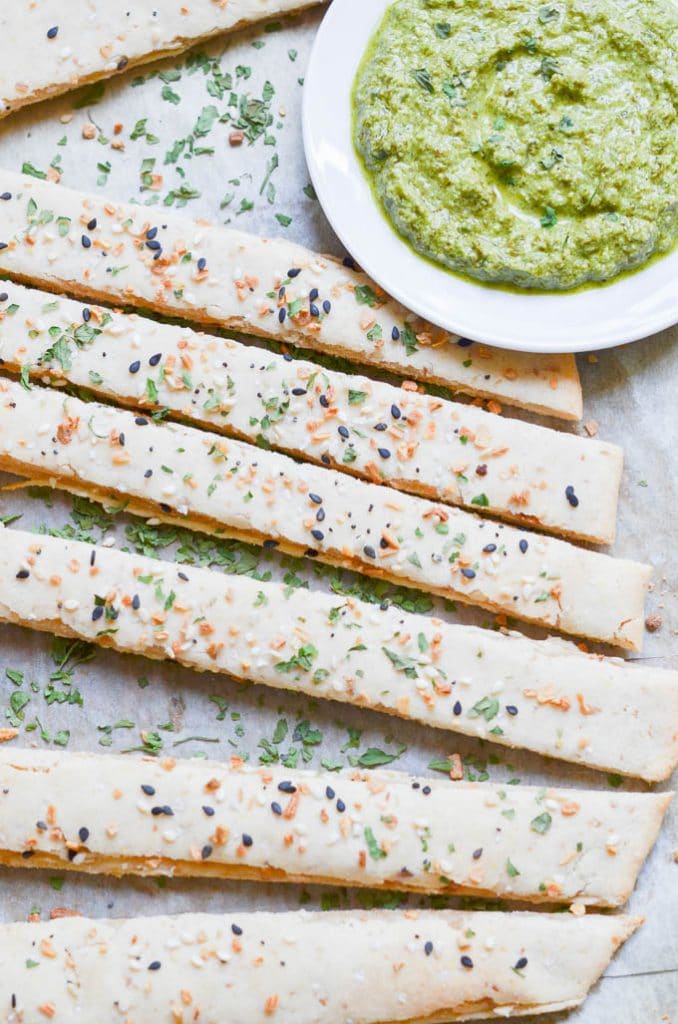 The Best Paleo Pizza Crust (vegan)! Paleo pizza dough made into breadsticks with pesto sauce in bowl.