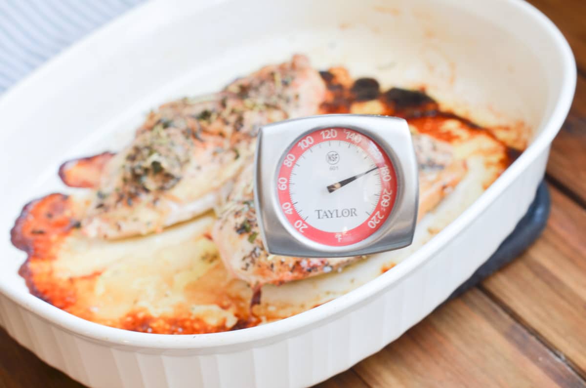 two baked chicken breasts in baking pan with meat thermometer at 170 degrees.