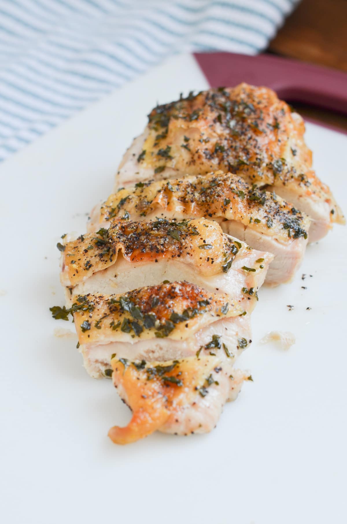 baked chicken breast sliced on cutting board.