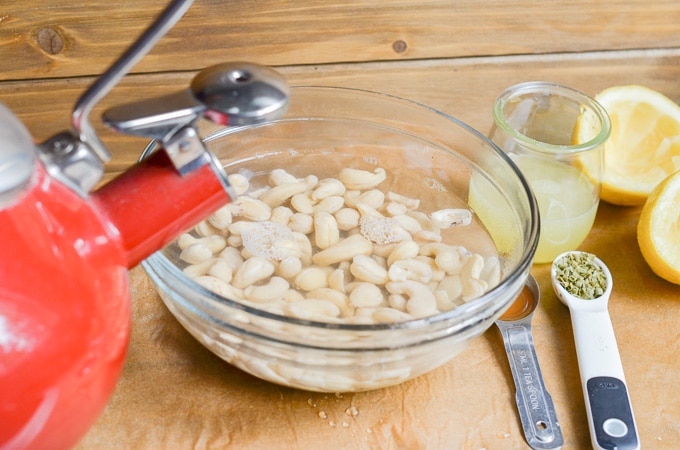 Cashews in bowl with kettle pouring hot water over cashews.