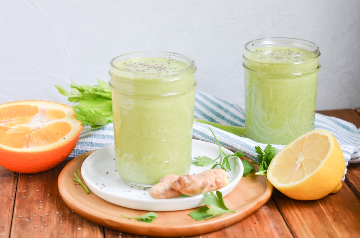 two green detox smoothies in glasses on counter.