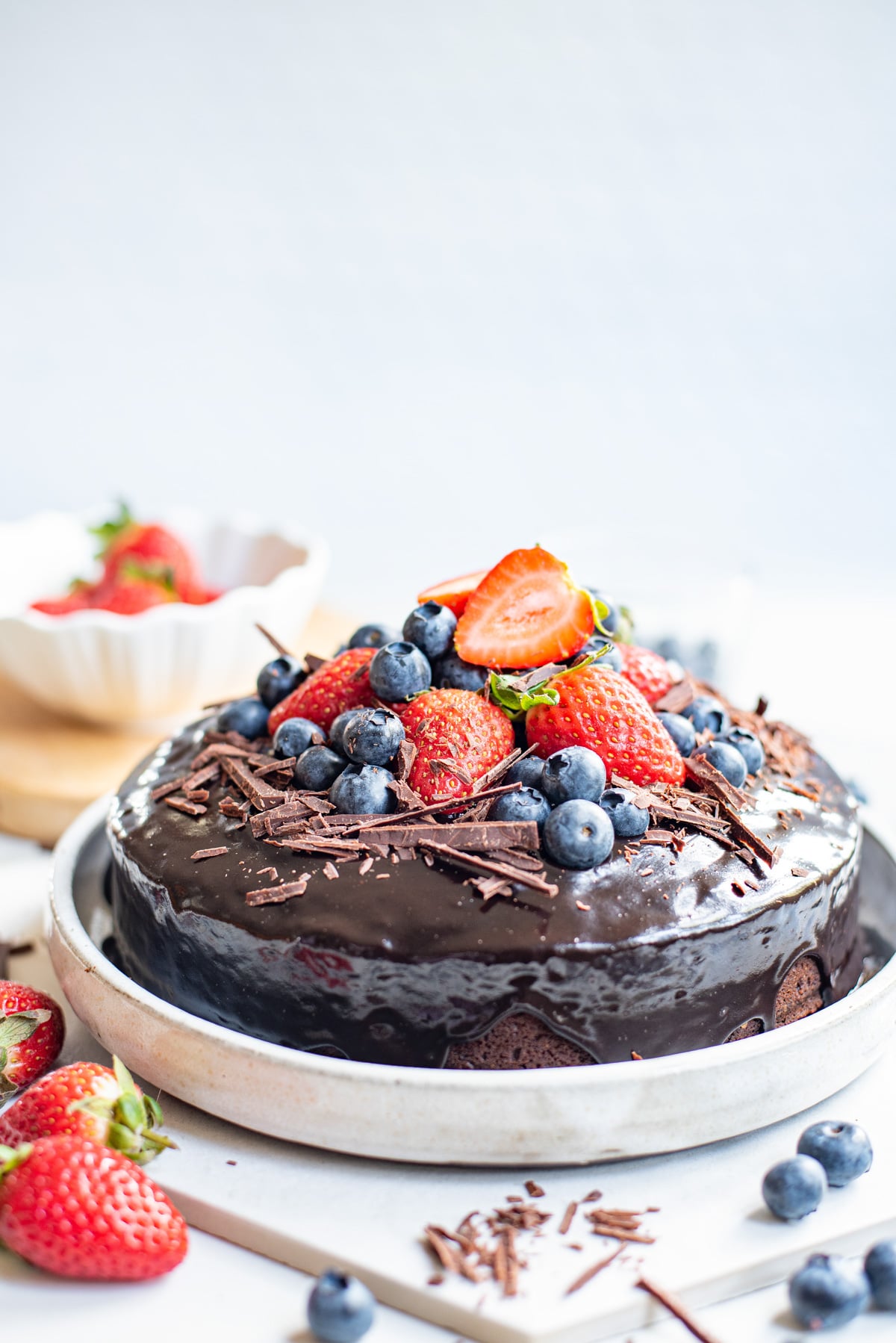 chocolate cake with icing and berries on cake stand.