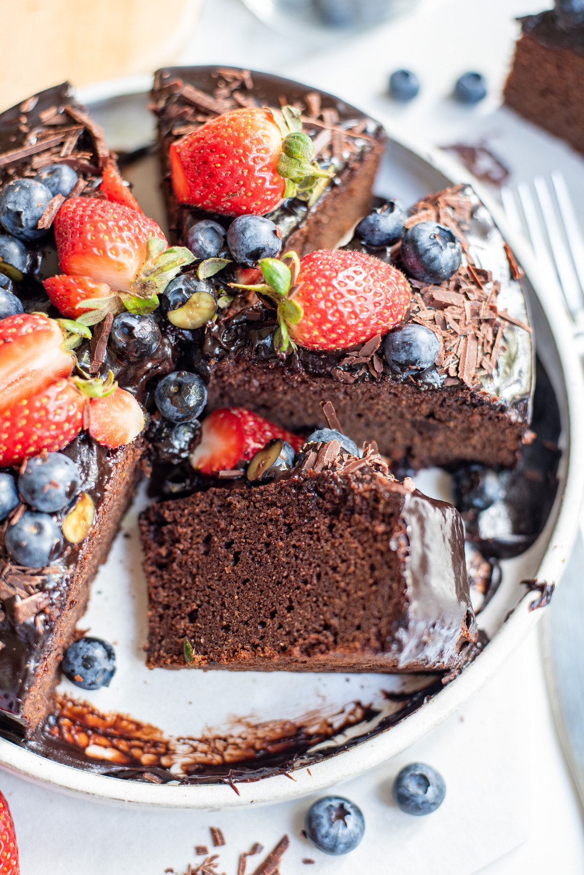 slice of paleo chocolate cake with icing and berries.