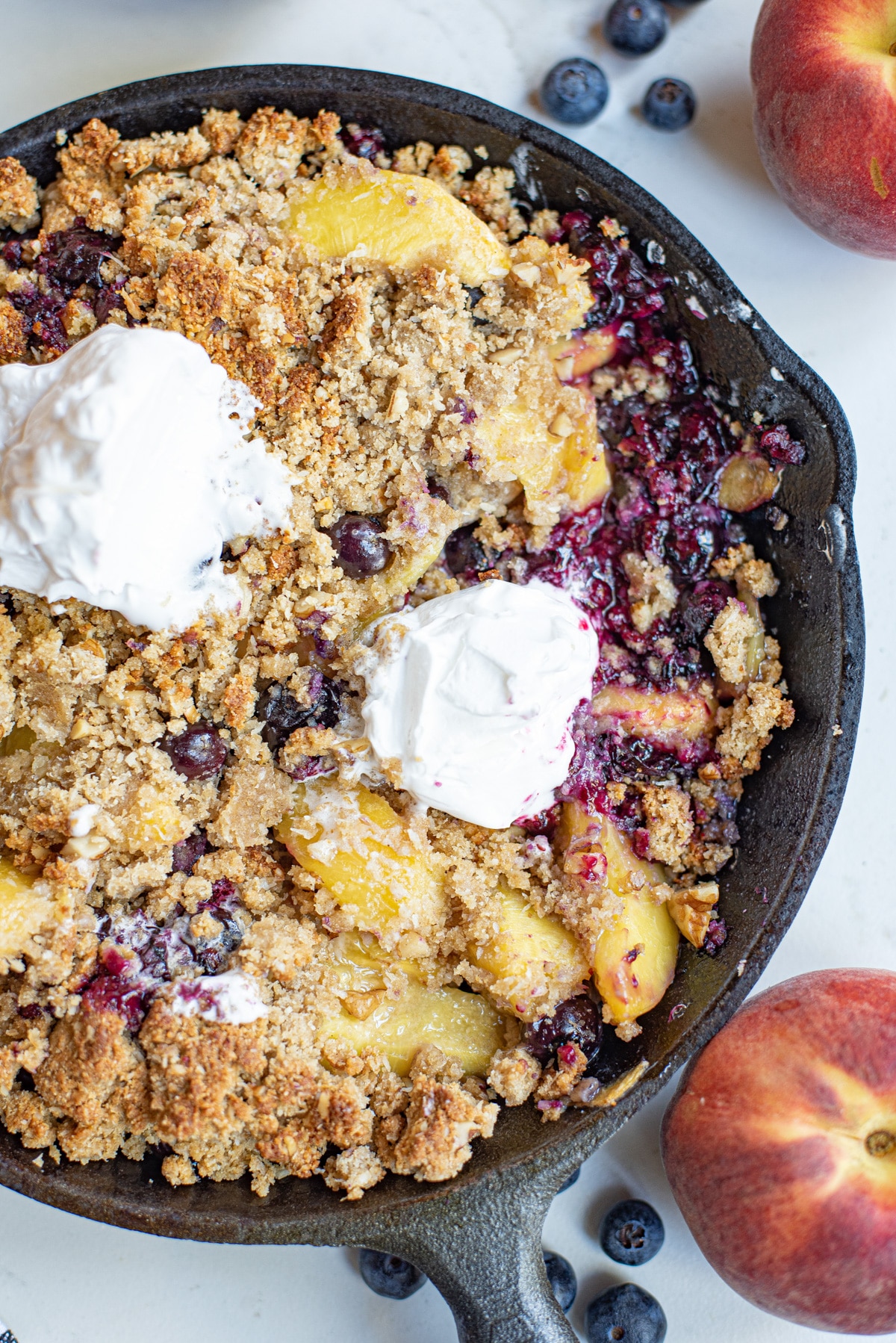 Baked peach blueberry crumble with whipped cream.