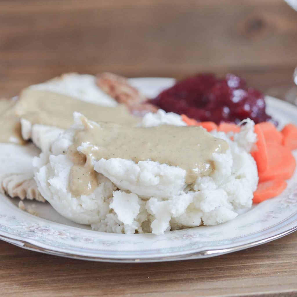 Whole30 Mashed Potatoes with gravy on plate with turkey, carrots, cranberry sauce