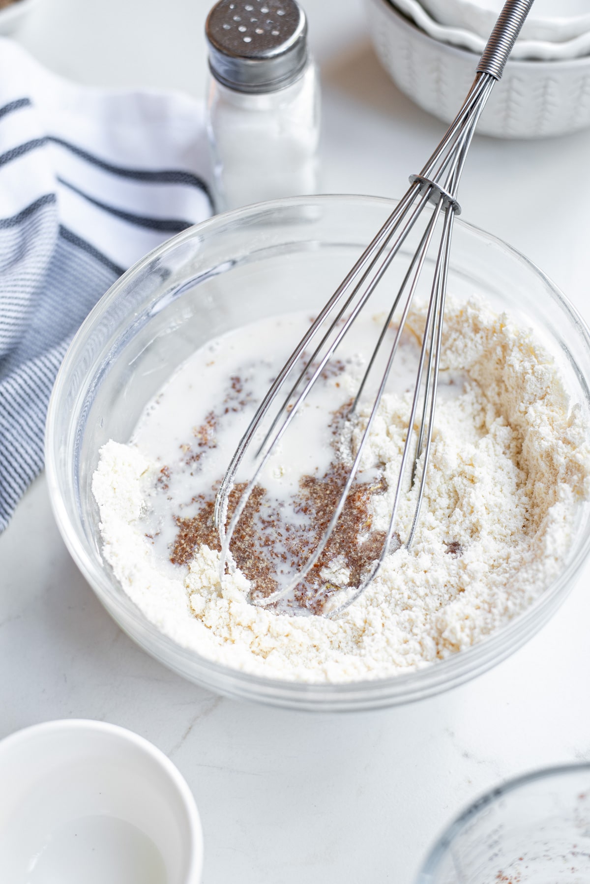 ingredients for pizza crust in bowl with whisk.