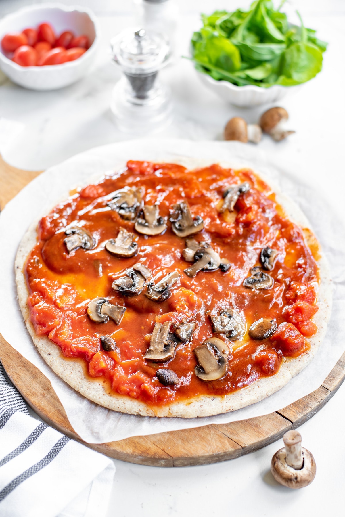 pizza crust topped with tomato sauce and mushrooms