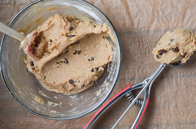 vegan cookie dough in mixing bowl with cookie dough in ice cream scoop.