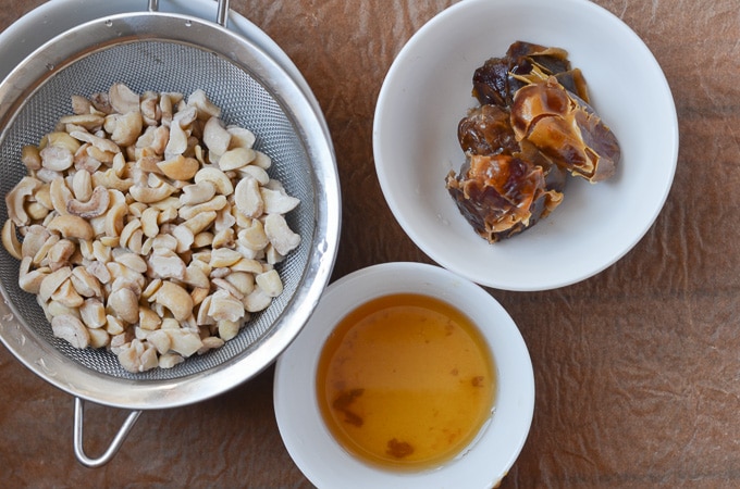 soaked cashew pieces drained and rinsed, bowl of soaked and drained dates and bowl of date water.