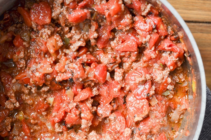 tomatoes, meat and spices in stock pot.