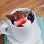 Paleo chocolate mug cake with berries and ice cream in mug.