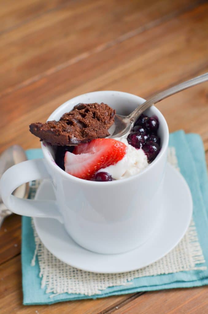 Paleo chocolate mug cake with berries and ice cream in mug.